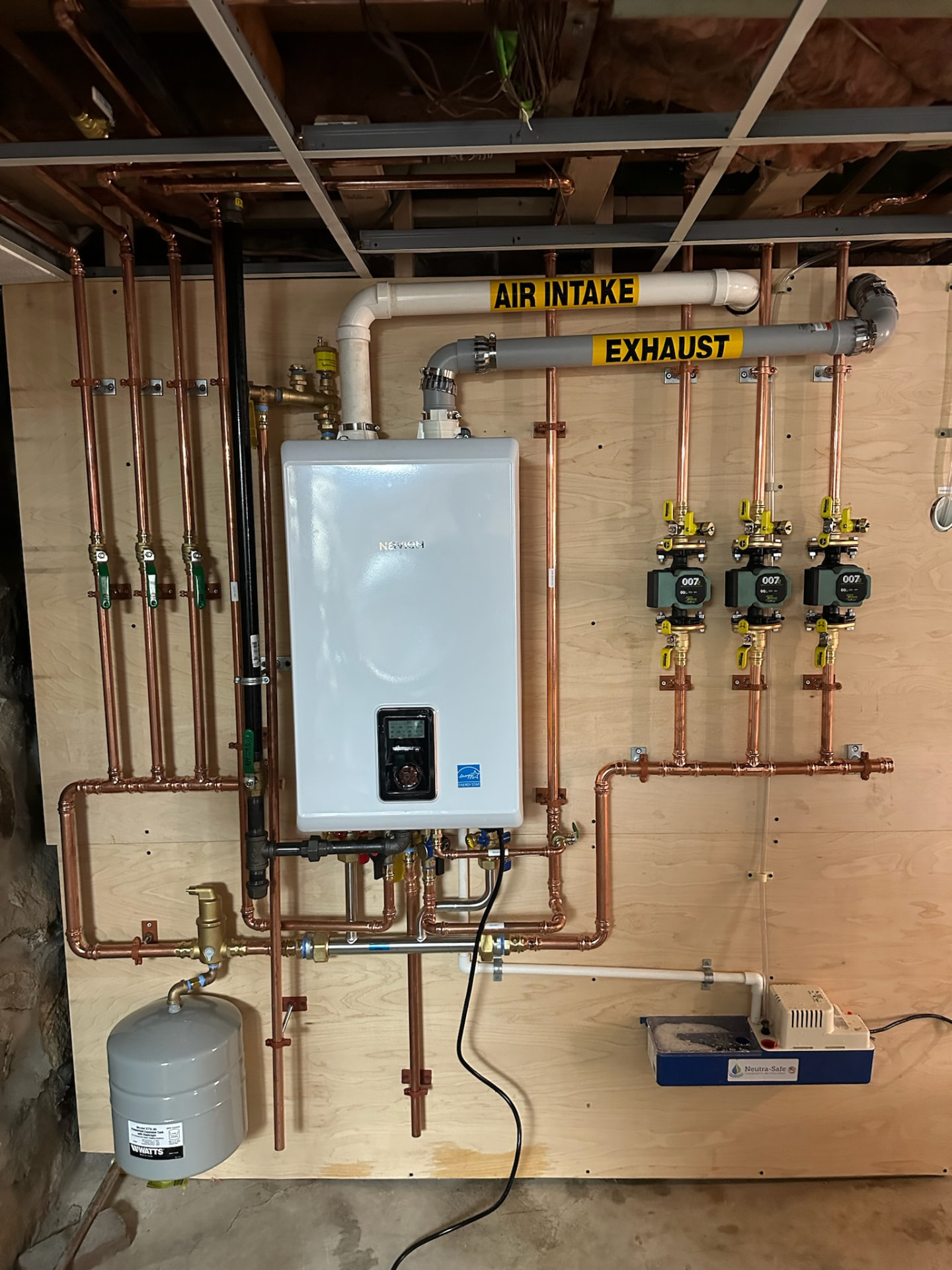 Navien wall-mounted unit installed by Bowden Plumbing & Heating with copper piping, labeled air intake and exhaust, and zone pumps